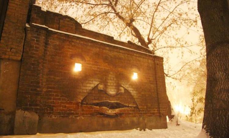 Face with glowing eyes painted on wall by Nikita Nomerz