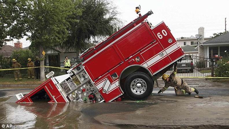 Wedged: A Los Angeles fireman looks under a fire truck stuck in a sinkhole in 2009